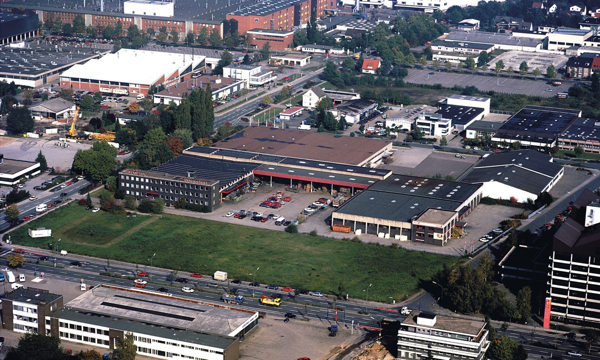 Luftaufnahme des Betriebsgeländes mit Hallen, Verwaltungsgebäude und umliegenden Straßen